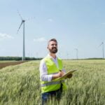 an engineer standing on a field on wind farm maki 9GVFPL5